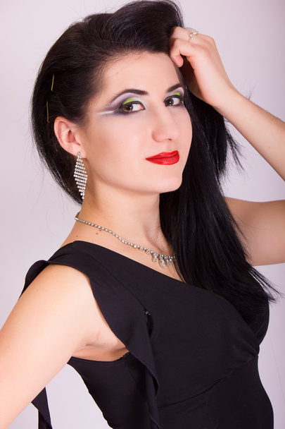 Beautiful slim young brunette woman in evening black dress and jewelry - Foto, afbeelding