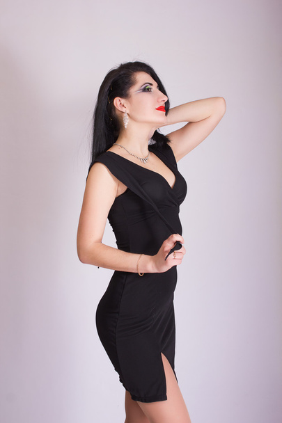 Beautiful slim young brunette woman in evening black dress and jewelry - Fotó, kép
