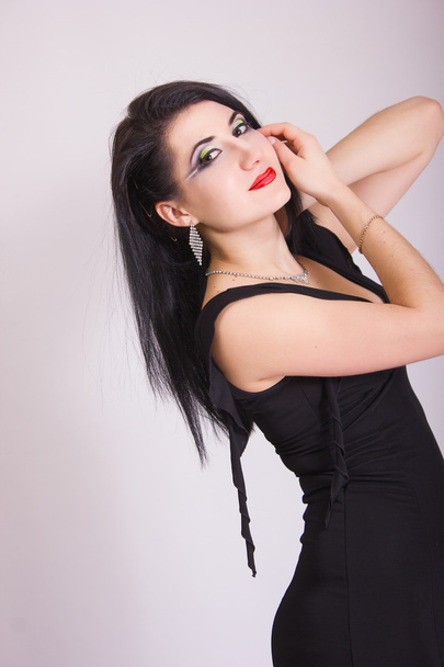 Beautiful slim young brunette woman in evening black dress and jewelry - Фото, зображення