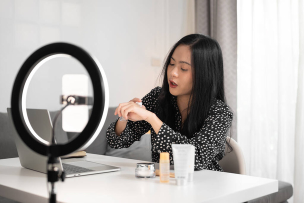 kobieta blogger pokazując swój produkt kosmetyczny przez smartfona na żywo wideo online. Biznes koncepcja online. - Zdjęcie, obraz
