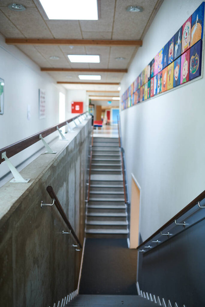 Escaleras bajando en una escuela con pinturas en la pared - Foto, imagen