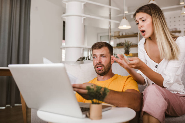 Portrait of young couple paying bills online using laptop and credit card.  - Φωτογραφία, εικόνα
