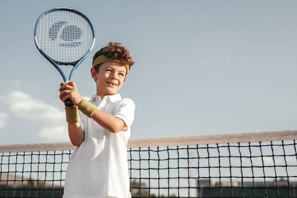 Happy boy playing tennis on court - Photo, Image