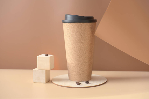 μοντέρνα κούπα καφέ και κόκκους καφέ σε μπεζ φόντο. καφέ για να πάει ή να πάρει μακριά ποτό σε επαναχρησιμοποιήσιμη κούπα. βιώσιμο και οικολογικό προϊόν. minimal στυλ.  - Φωτογραφία, εικόνα