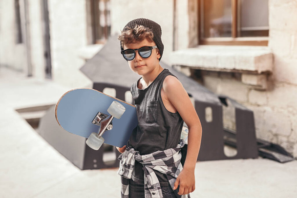 Hipster kid with skateboard on street - Fotoğraf, Görsel