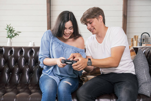 Een man die zijn vrouw spelletjes leert spelen met joystick. Een vrolijke glimlach. Ze ontspannen in een gezellig interieur. - Foto, afbeelding