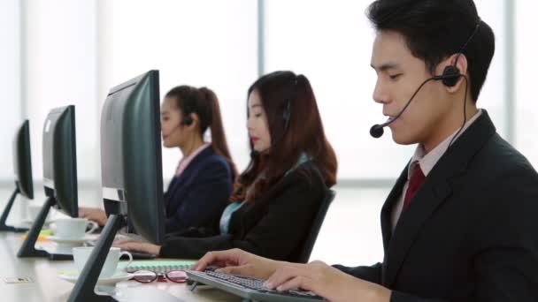 Vezetékes fülhallgatót viselő üzletemberek az irodában - Felvétel, videó