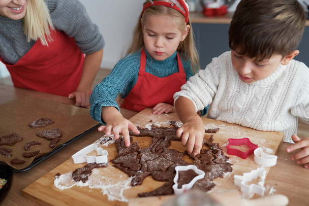 Hoge hoek uitzicht van kinderen snijden peperkoek koekjes  - Foto, afbeelding