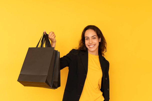 Черная пятница посреди фотографии радостной женщины с черной сумкой для покупок - Фото, изображение