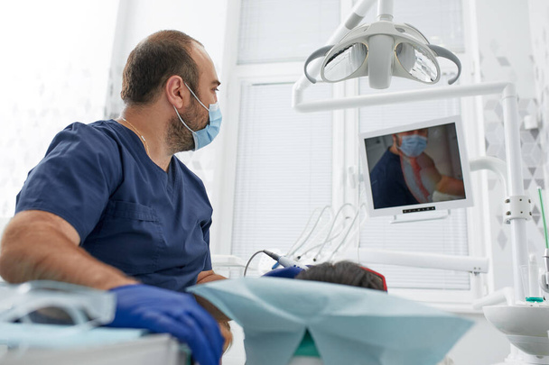emberek, gyógyszer, fogtechnika és egészségügyi koncepció - boldog férfi fogorvos női beteggel a fogászati klinika irodájában - Fotó, kép