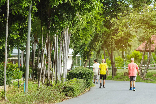 Widok z tyłu Portret Azjaty w stroju fitness spacerującego i biegającego dla dobrego zdrowia w parku publicznym. Starszy jogger w naturze. Starszy człowiek cieszący się spokojną naturą. Koncepcja opieki zdrowotnej. - Zdjęcie, obraz