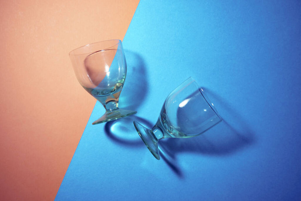美しい抽象的な背景ワインのガラスの光の線は、黄色と青のパステルカラーの背景を屈折、抽象的なデザイン明るい楽しいフラットレイ、カラフルな背景にガラスの影を通して光. - 写真・画像