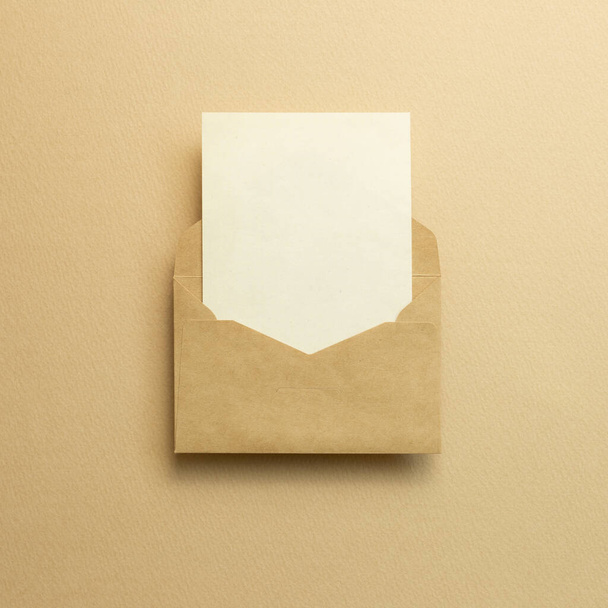 Порожня картка в крафт-конверті на бежевому фоні. вид зверху, місце для копіювання
 - Фото, зображення