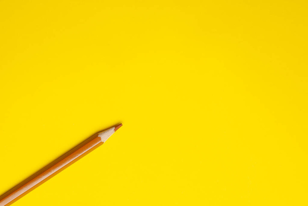 diagonal light brown sharp wooden pencil on a bright yellow background, isolated, copy space, mock up - Фото, зображення