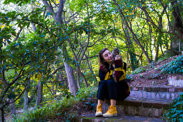 Žena a kočka v botanické zahradě a parku, stromy a ležérní mladá dívka portrét v zahradě - Fotografie, Obrázek