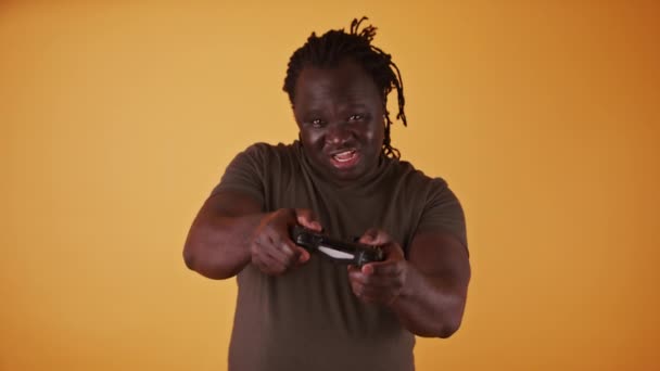 uomo africano con controllore di gioco isolato su sfondo arancione - Filmati, video