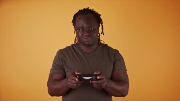 Afrikaanse man met game controler geïsoleerd op oranje achtergrond - Video