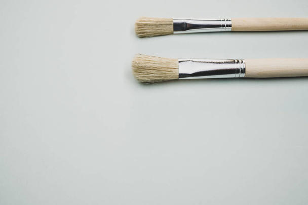 A closeup shot of the paintbrushes on the gray surface - Fotó, kép