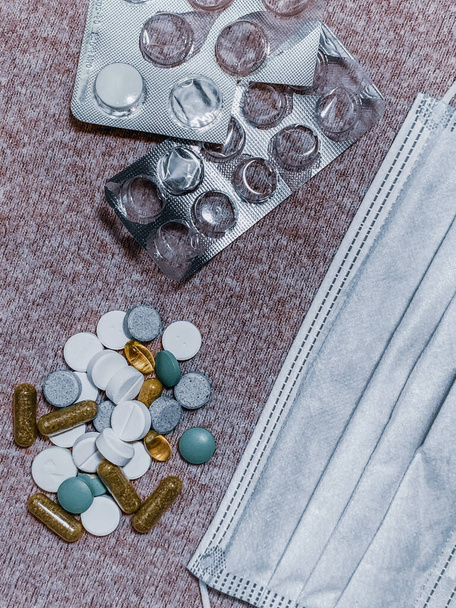 A vertical top view of pills and capsules and a medical mask - Zdjęcie, obraz