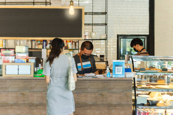 Социальная дистанция концептуальный малый бизнес официант, обслуживающий клиента в кафе - Фото, изображение