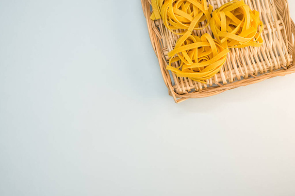 A closeup shot of tagliatelle pasta on a wicker plate - Фото, изображение