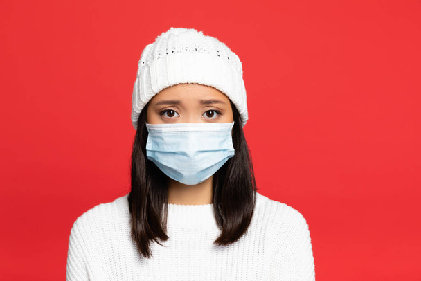 joven asiático mujer en médico máscara y sombrero aislado en rojo - Foto, Imagen