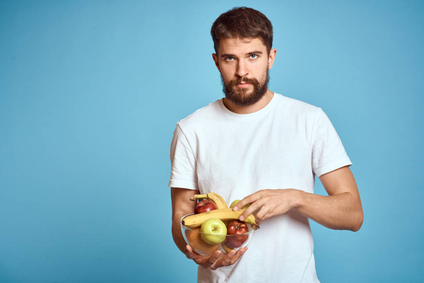 fondo oscuro hombre guapo con una barba sosteniendo fruta fresca y estilo de vida taza transparente - Foto, Imagen