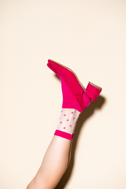 cropped view of female leg in pink retro socks and shoes on beige background - Photo, Image