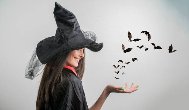 fiatal nő boszorkány halloween jelmez kalap áll, és mosolyog a fehér háttér - Fotó, kép
