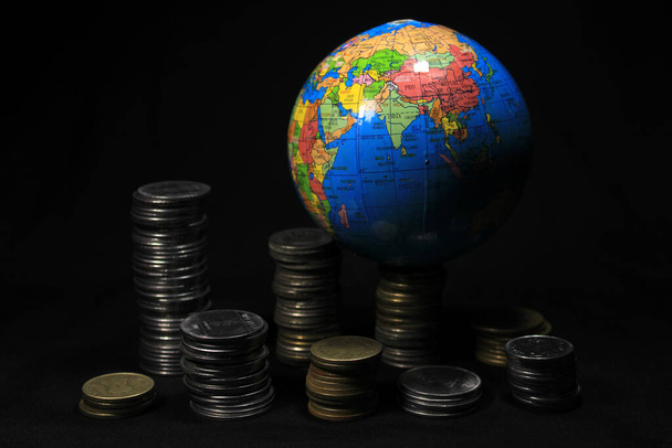 Фондовая куча из 1, 2, 5, 10 индийских рупий металлическая монета с глобусом изолированы на черном фоне. Финансовая, экономика, инвестиционная концепция. - Фото, изображение