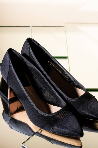 κομψά μαύρα τακούνια παπούτσια στην επιφάνεια του καθρέφτη - Φωτογραφία, εικόνα