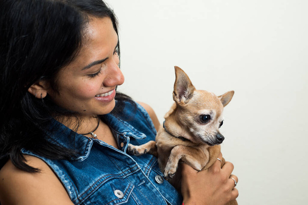 A Latin woman holding her brown chihuahua - Foto, immagini