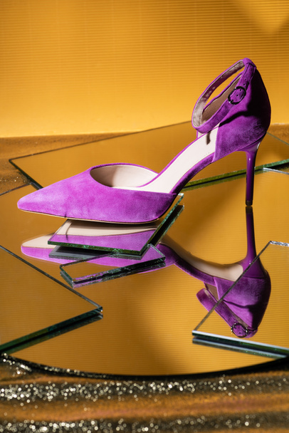 elegante zapato de tacón de ante violeta en la superficie del espejo sobre fondo amarillo - Foto, imagen