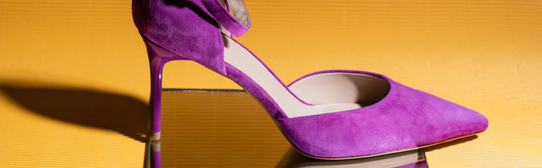 elegant violet suede heeled shoe on mirror on yellow background, banner - Foto, imagen