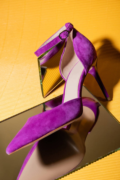 elegant violet suede heeled shoe on mirror on yellow background - Φωτογραφία, εικόνα