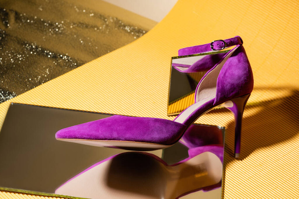 elegant violet suede heeled shoe on mirror on yellow background - 写真・画像