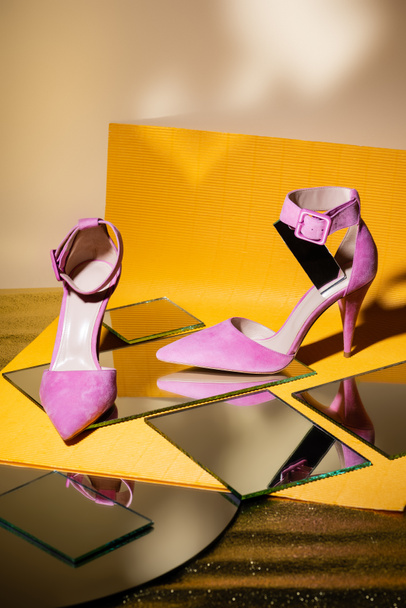 elegant violet suede heeled shoes on mirror and yellow paper - Fotó, kép