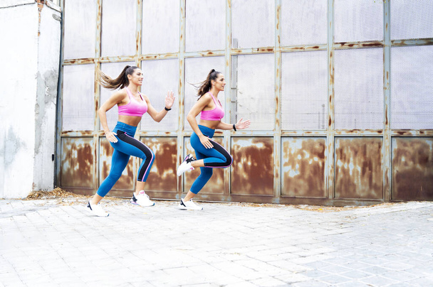 Caucasian sporty sisters running during the outdoors workout - Photo, image