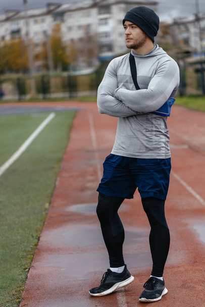 Confident smiling athletic adult male trainer in a tracksuit arms crossed over his chest and looking at the camera - Photo, Image