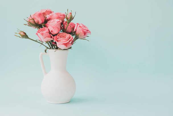 Bouquet of pink roses in white vase on light blue background. Copy space - Fotoğraf, Görsel