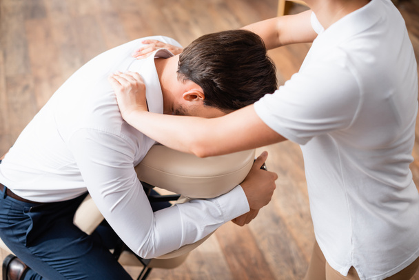 Masseuse doing seated massage of businessman shoulders in office - Zdjęcie, obraz