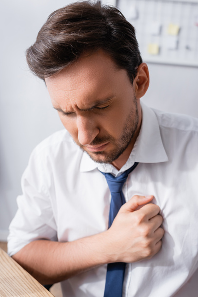 Close up view of office worker suffering from chest pain in office on blurred background - Fotografie, Obrázek
