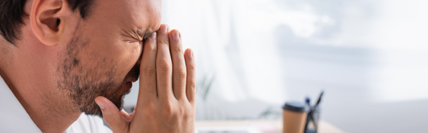 Zijaanzicht van uitgeputte kantoormedewerker met biddende handen, last van migraine op wazige achtergrond, spandoek - Foto, afbeelding