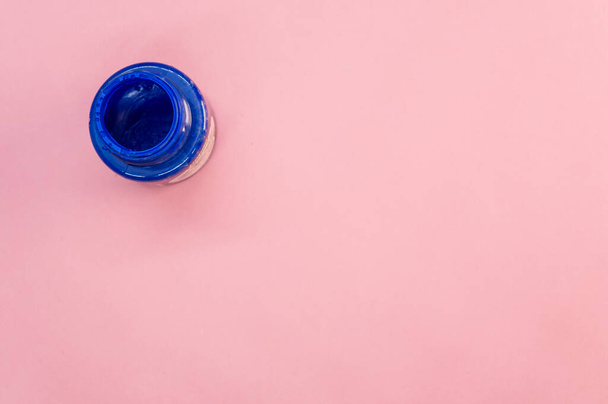 A top view of the acrylic blue paint in the bottle on pink surface - Fotografie, Obrázek