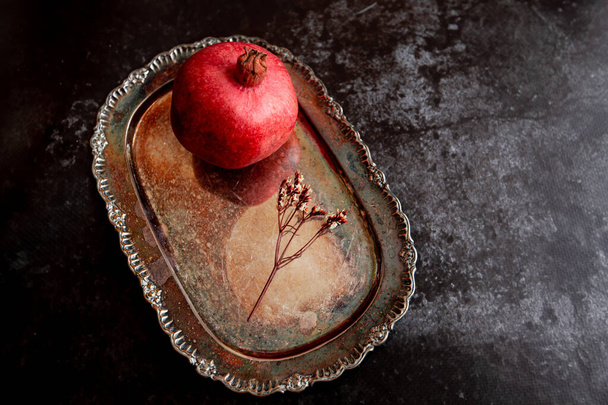 frischer Granatapfel auf einem wunderschönen Vintage-Tablett auf dunklem Hintergrund - Foto, Bild