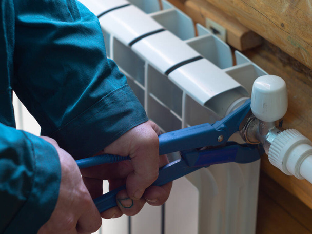 the man tightens the nut on the radiator. installation of heating batteries. plumber's job. - Фото, изображение