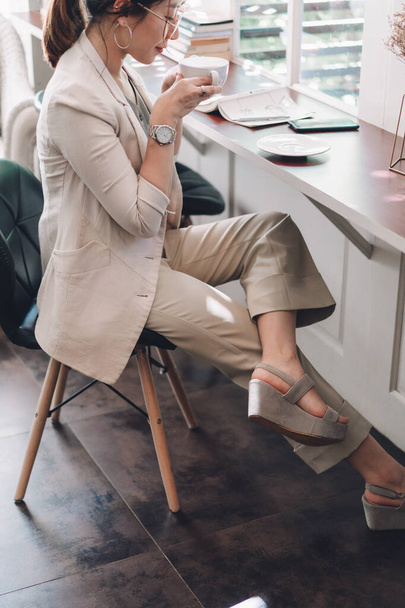 テーブルの上でコーヒーを飲みながら働くビジネス女性は - 写真・画像
