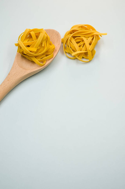 A vertical shot of tagliatelle pasta and a wooden kitchen tool - Foto, afbeelding
