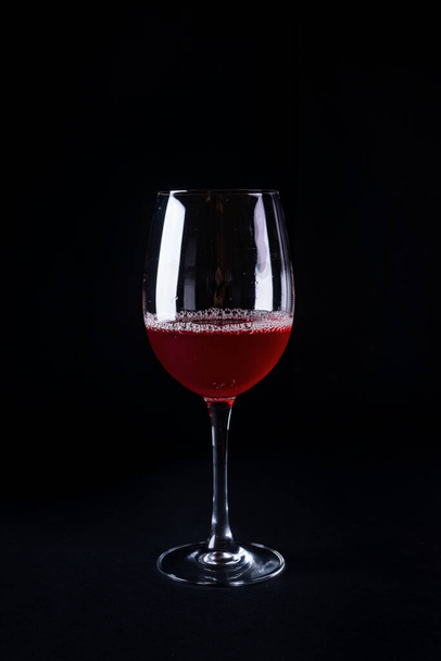 A vertical shot of a glass of red wine on a black background - Fotó, kép