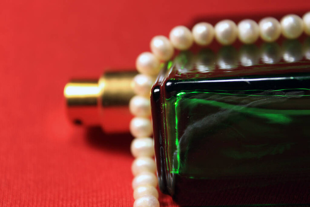 Zöld színű parfüm palack női tartozékok elszigetelt piros háttér. - Fotó, kép